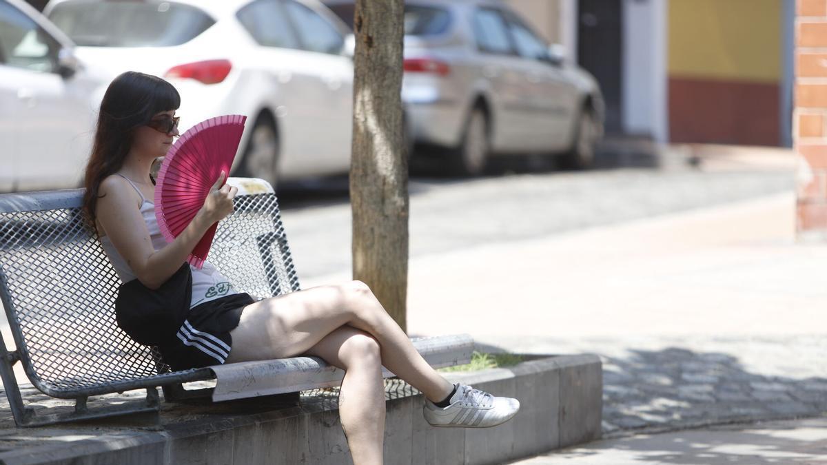Una chica se abanica en un banco de Zaragoza a la sombra durante una ola de calor