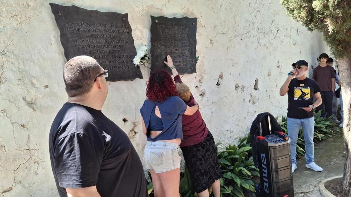 Teresa, sostenida por Irene, acaricia la placa en la que está el nombre de su familiar