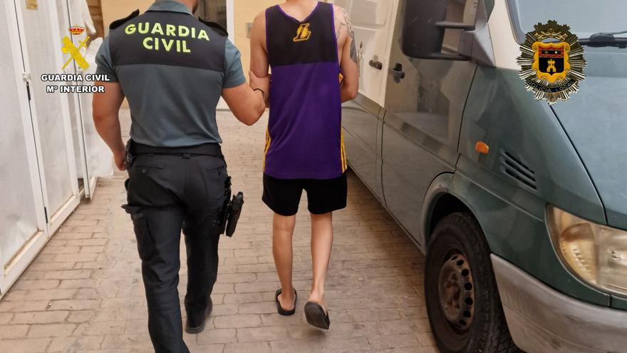 Un agente de la Guardia Civil custodia a uno de los detenidos en el marco de la operación 'Anochecer'