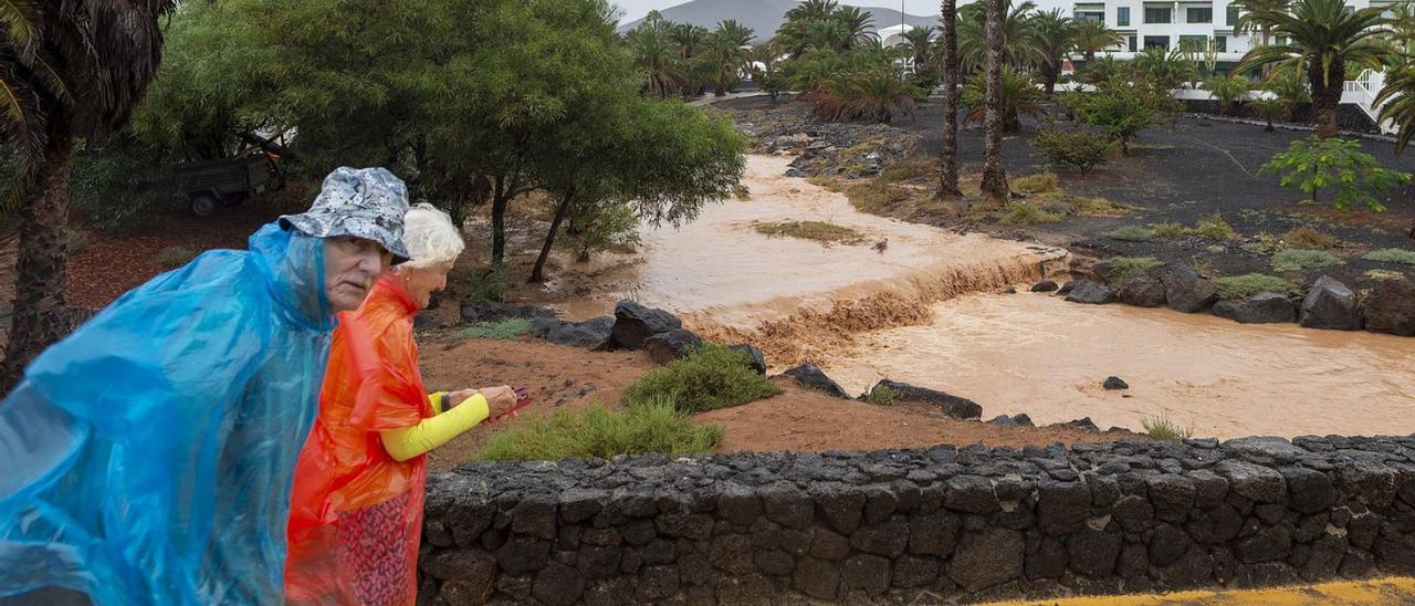 Unos turistas observan el barranco que desemboca en la playa de Las Cucharas, en Costa Teguise, Lanzarote. | Efe