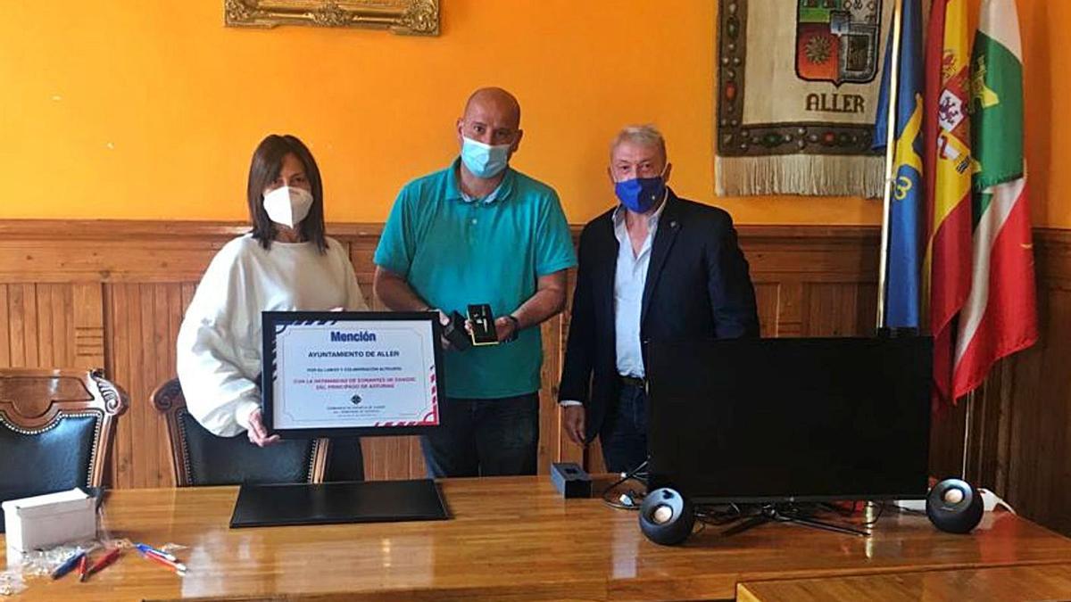 Eugenia García y Juan Carlos Iglesias sostienen el diploma en presencia del coordinador de donantes en el Caudal.