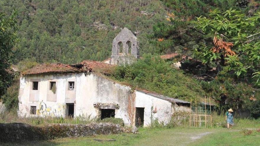 Uno de los edificios anexos a San Antolín de Bedón, en ruinas, con la torre de la iglesia al fondo.