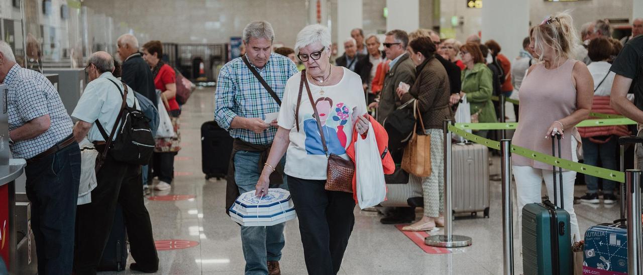 Pasajeros con una caja de ensaimadas en el aeropuerto de Palma.