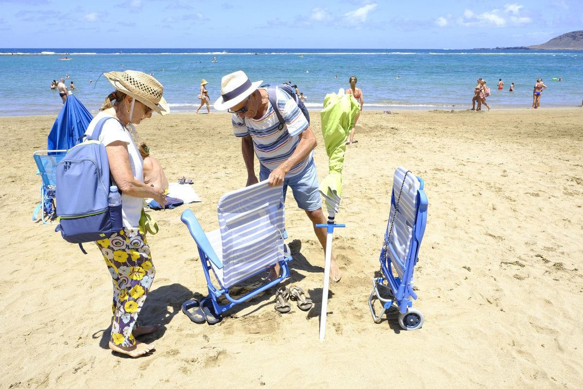 Una pareja recogiendo sus utensilios en la playa de Las Canteras