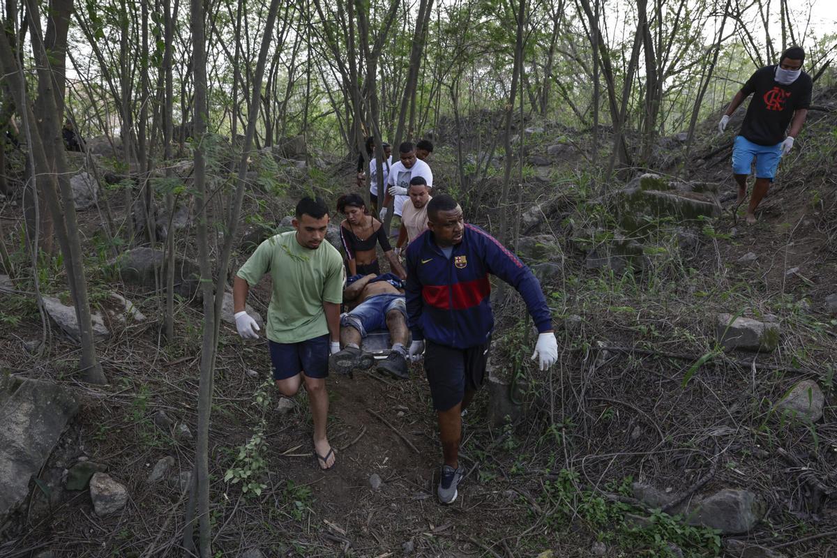 Personas retiran un cuerpo sin vida de una zona boscosa este miércoles, en la favela Vila Cruzeiro en Río de Janeiro (Brasil). EFE/ André Coelho. ATENCIÓN EDITORES: CONTENIDO GÁFICO EXPLICITO ACOMPAÑA CRÓNICA: BRASIL DROGAS