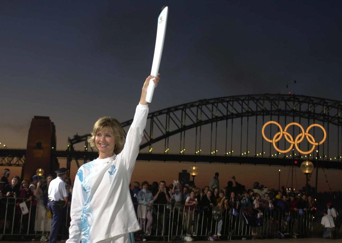 La cantante y actriz australiana Olivia Newton John alza la antorcha con la Llama Olímpica para mostrarla a las miles de personas que se congregaron esta tarde en el puerto de Sydney para recibirla.