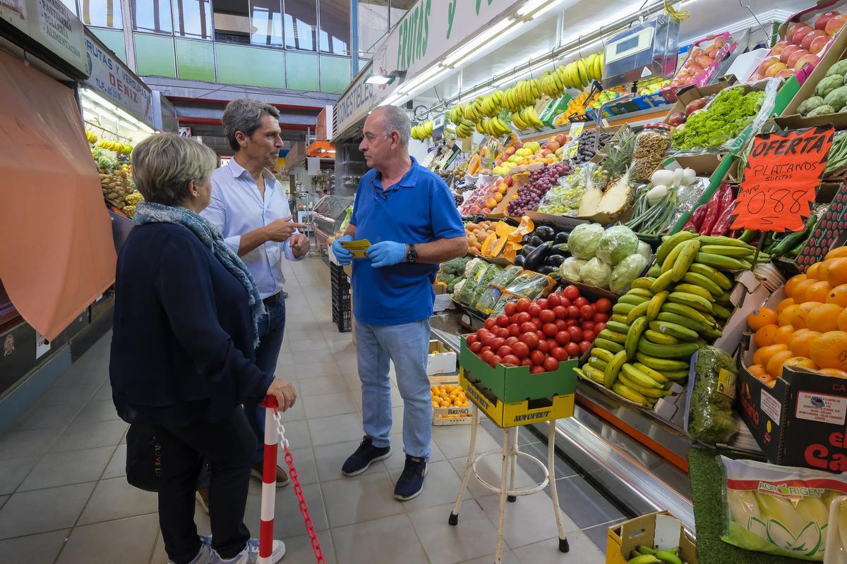 Los candidatos de UxGC Enrique Hernández Bento y Carmen Guerra conversan con un puestero en el mercado de Altavista