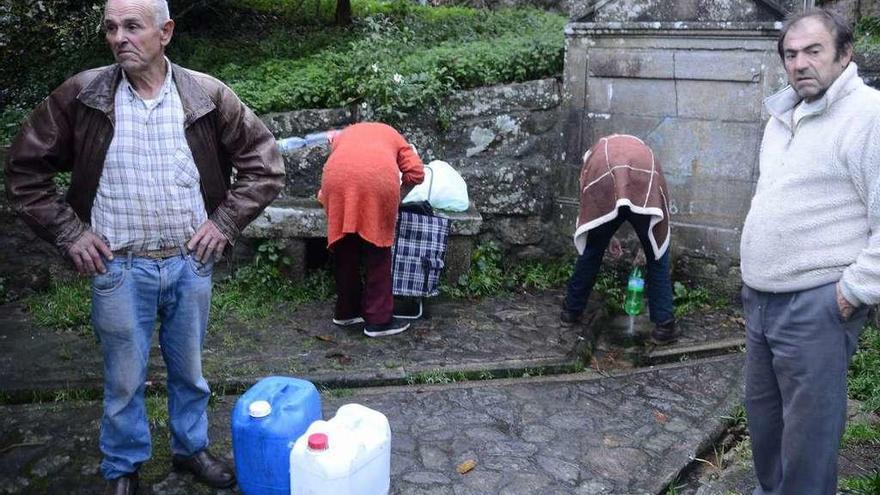 Un grupo de vecinos se abastece de agua en una fuente de la parroquia de Darbo. // G.Núñez