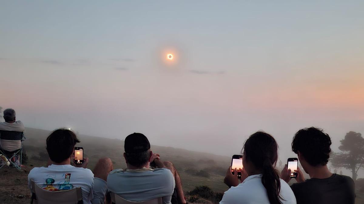Personas siguiendo el eclipse desde Tineo, en el momento que la Luna se superpone al Sol.