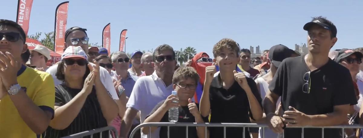 Numeroso público agolpado detrás de las vallas para ver el paso de los ciclistas en la playa de Puçol.