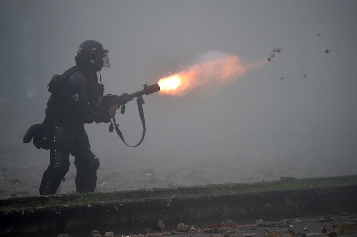 Un policía dispara su arma de gas lacrimógeno contra los manifestantes en las protestas en la ciudad de Cali.