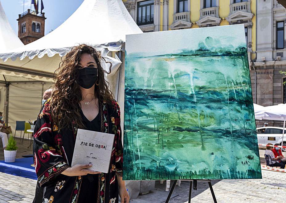 Sara Canteli posa con su libro y su cuadro, ayer, en Porlier. | Nazaret Quintas