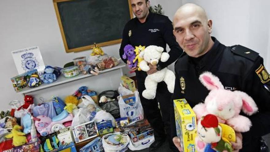 El policía promotor de la campaña, en primer plano, junto a otro agente muestra los juguetes recogidos.