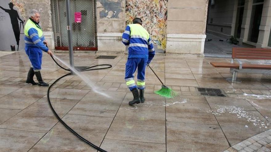 Dos operarios regando una calle de Málaga.