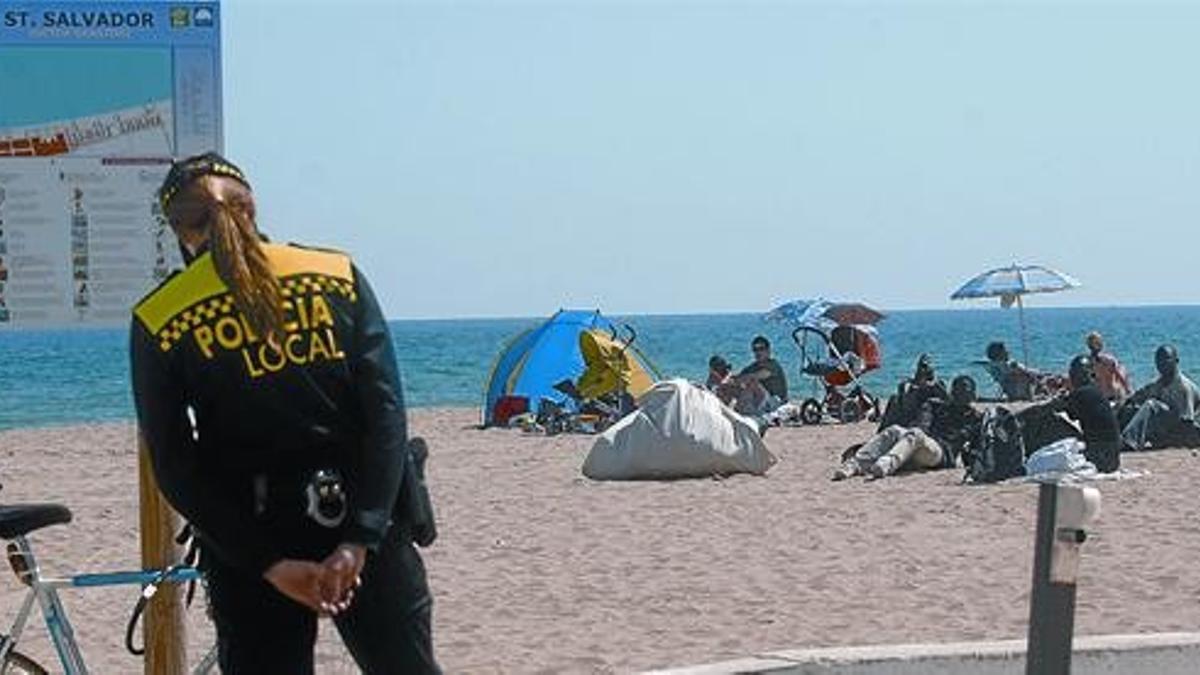 Vigilancia 8 Dos policías locales de El Vendrell vigilan a un grupo de manteros apostados en la arena de la playa, el jueves.