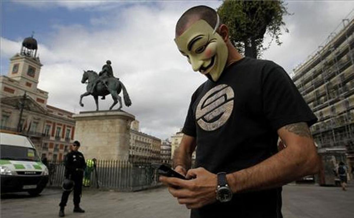 Un home es tapa la cara davant la policia durant el desallotjament dels últims indignats de la Puerta del Sol, a Madrid.