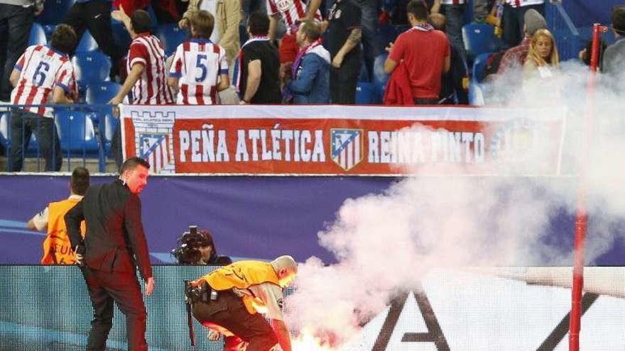 Un miembro de la seguridad del Atlético recoge una bengala lanzada al campo.