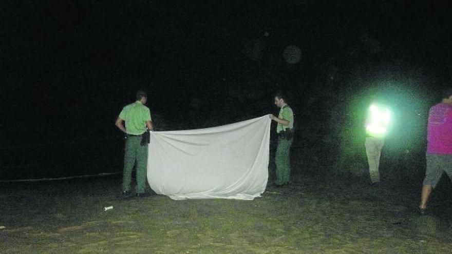 Dos agentes cubren el cuerpo hallado en el Marenyet, mientras esperan a la comisión judicial.