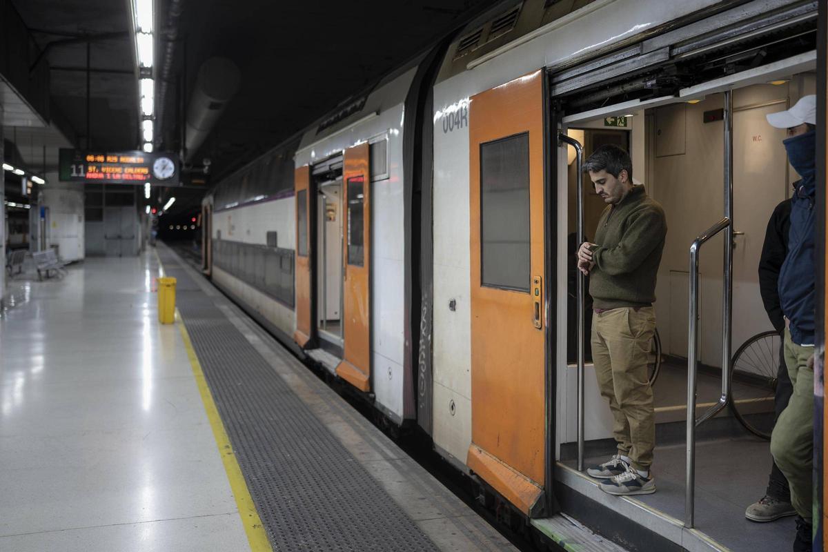 Un pasajero de Rodalies mira el reloj en un tren parado.