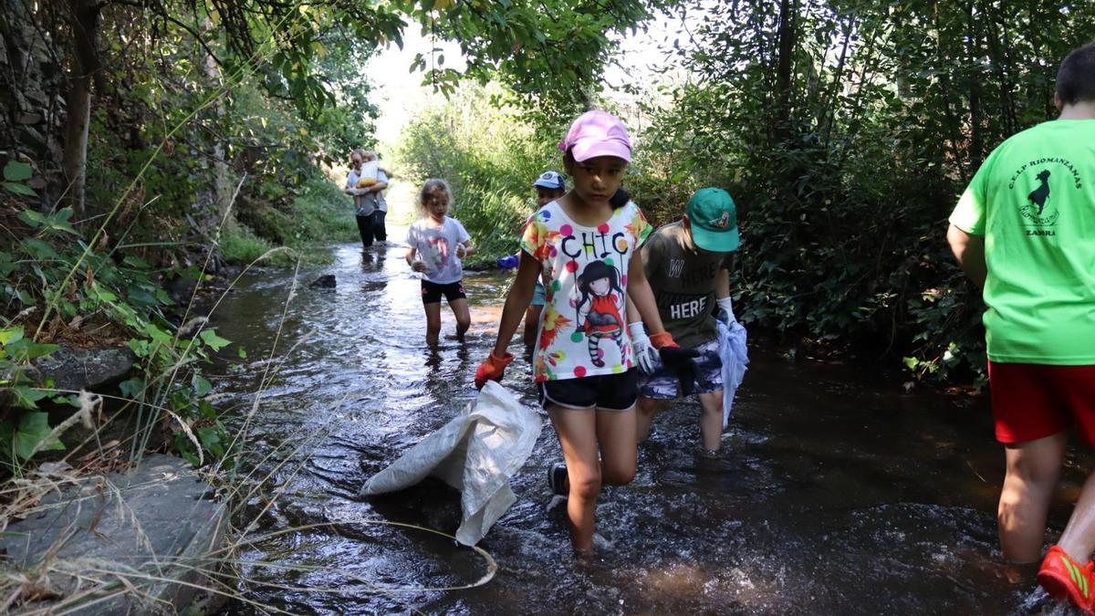 Los niños y las niñas metidos en el río Frío para dejaro limpio de basura.