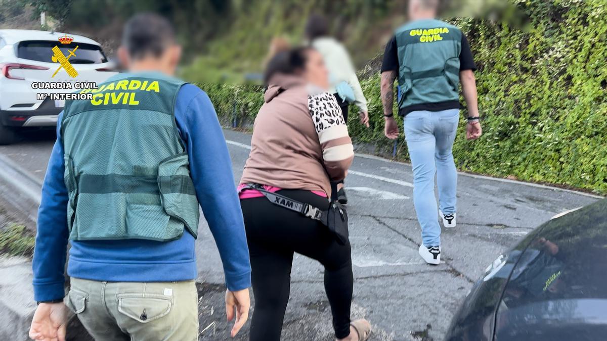 Dos agentes de la Guardia Civil con varias de las personas detenidas.