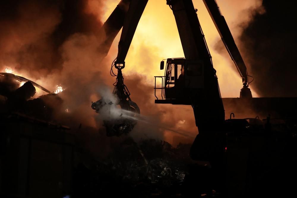 Labores de extinción del incendio de un desguace en Gijón