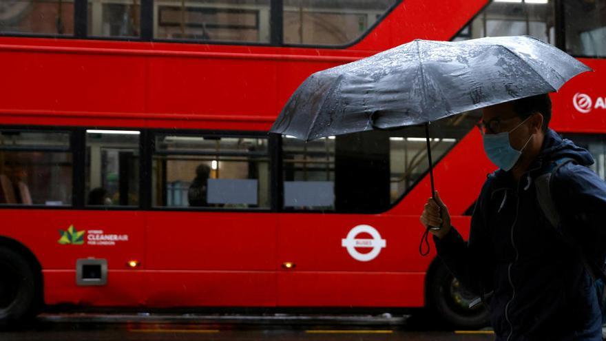 Un hombre con paraguas y mascarilla en el centro de Londres