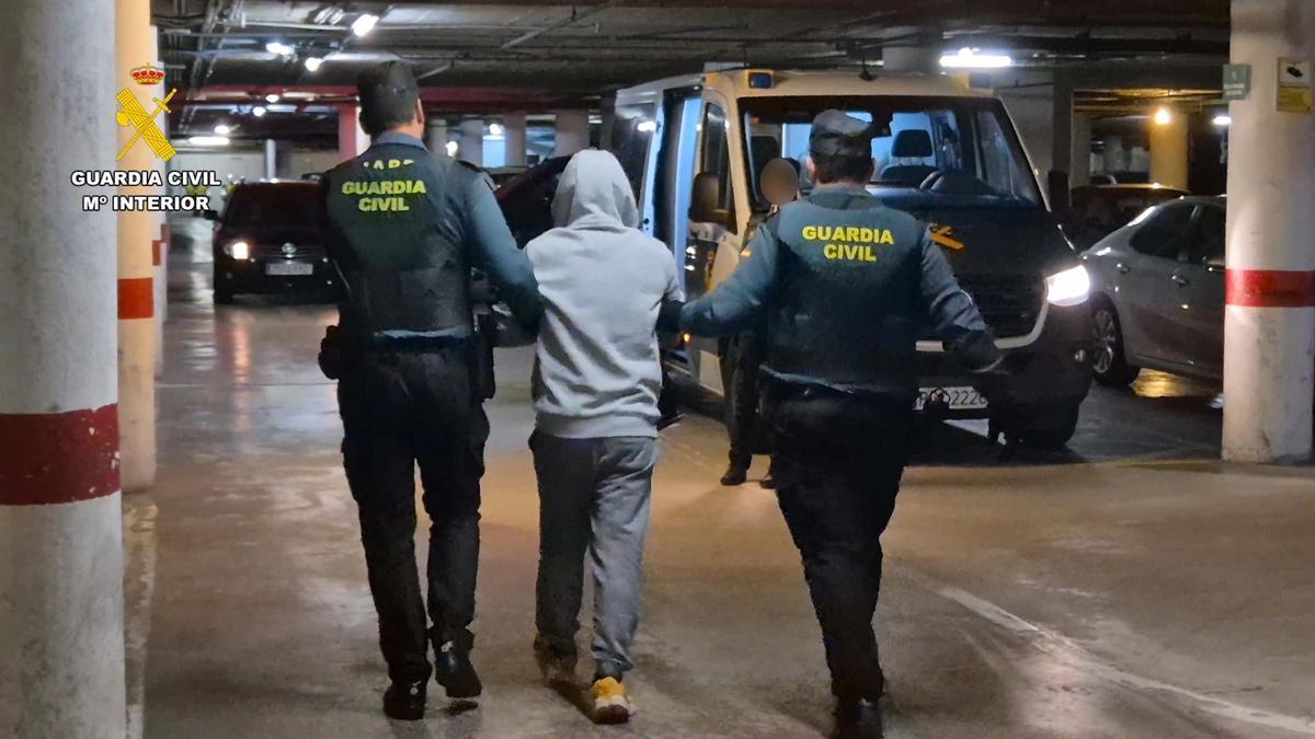 Agentes de la Guardia Civil llevan detenido a uno de los presuntos proxenetas.