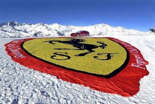 A Ferrari FF car is displayed next to a Ferrari logo during the Wrooom, F1 and MotoGP Press Ski Meeting in Madonna di Campiglio