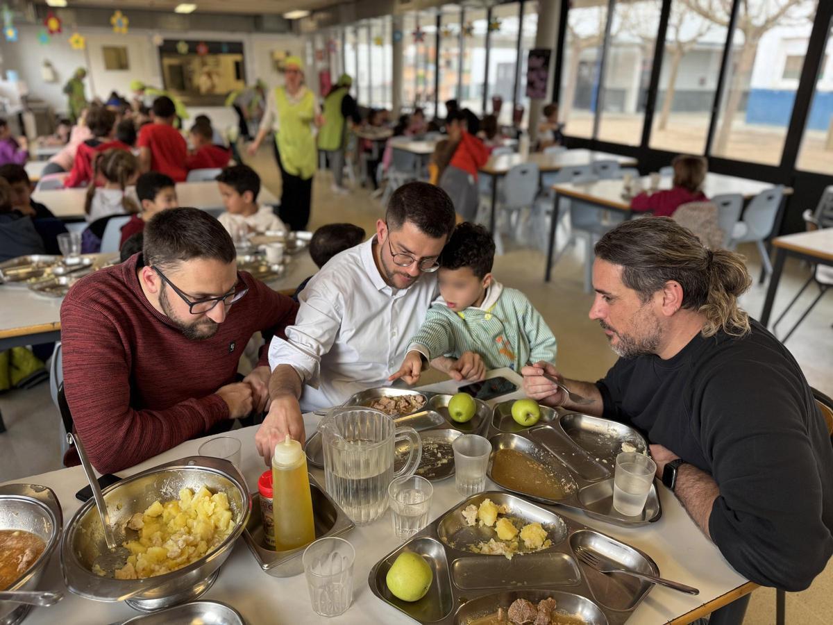 Eloi Hernàndez (al mig), acompanyat d'Enric Forcada i Jordi Palma, escolta un nen al menjador de l'escola Doctor Ferrer