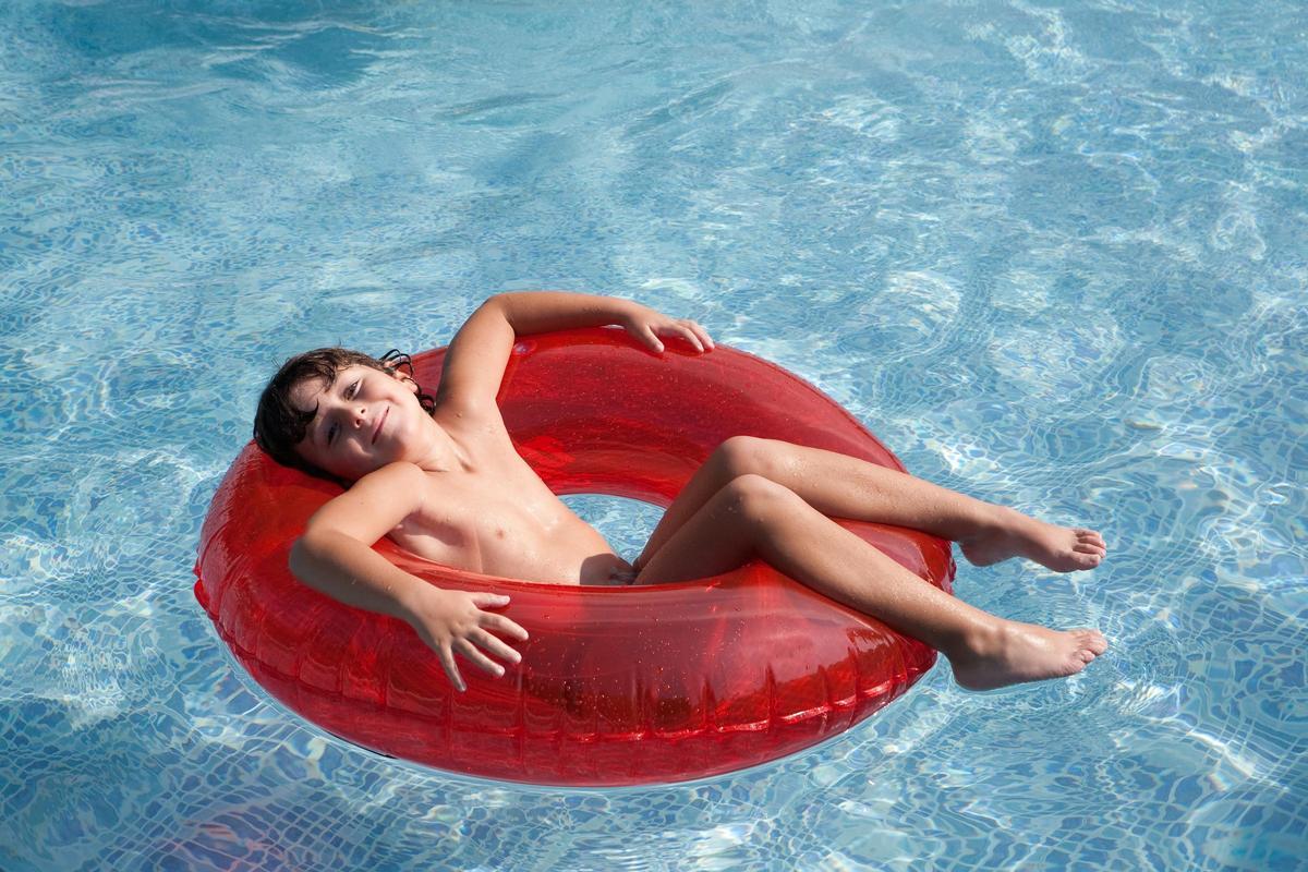 Un  niño difruta en una piscina con  un hinchable