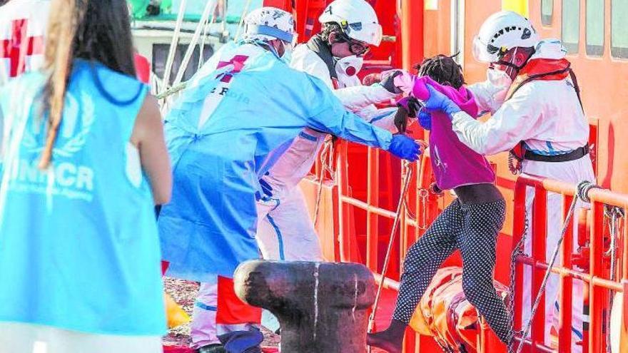 Momento en que ayudan a un menor migrante a desembarcar, el pasdo miércoles, en el muelle de Arguineguín (Gran Canaria).