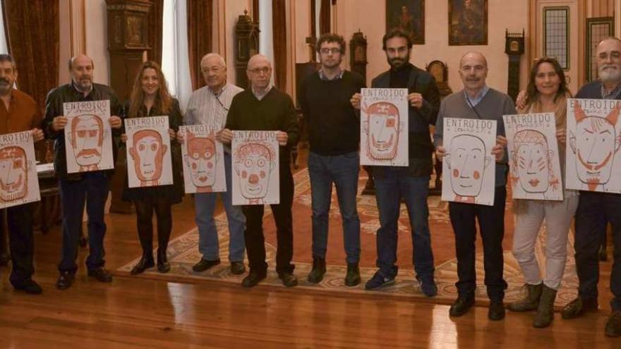 El concejal de Culturas, en el centro, posa con representantes de las comparsas, que sostienen las diferentes versiones del cartel de este año.