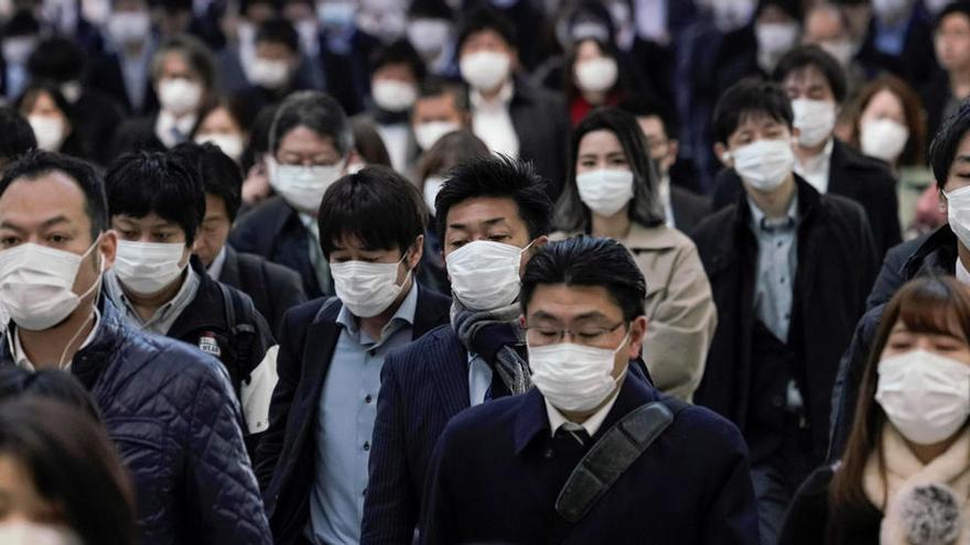 Trabajadores protegidos con mascarillas acuden a sus oficinas en Tokio.