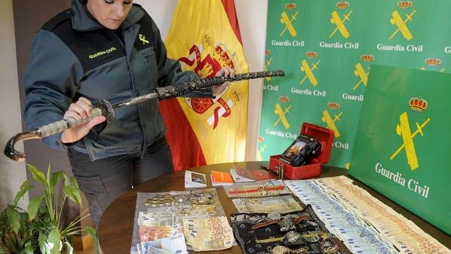 Una agente examina una katana junto a una mesa con otros objetos intervenidos. // Brais Lorenzo