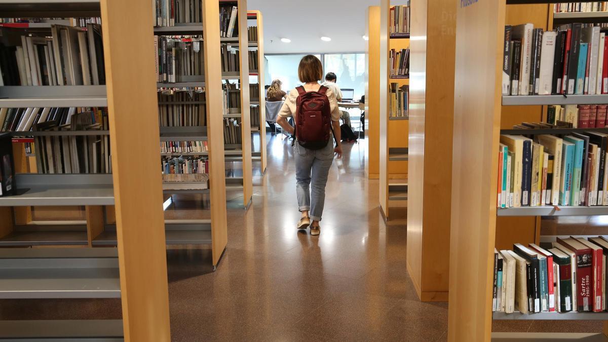 Una joven, entra en una biblioteca de Barcelona para estudiar.