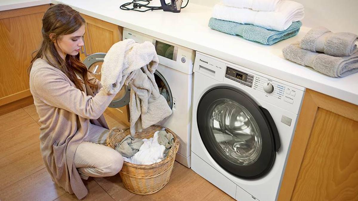 Mujer introduciendo ropa en una secadora doméstica
