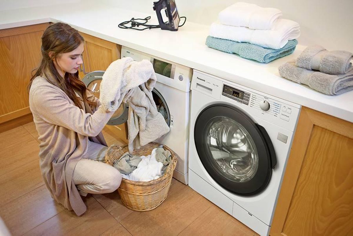 Mujer introduciendo ropa en una secadora doméstica