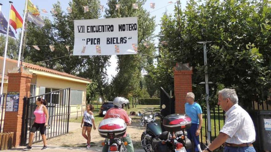 Varias personas junto al cartel anunciador del encuentro motero.