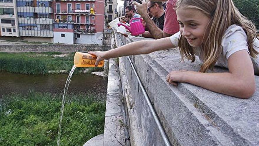 Diferents persones llançant aigua al riu Onyar, des del pont de Pedra de Girona.
