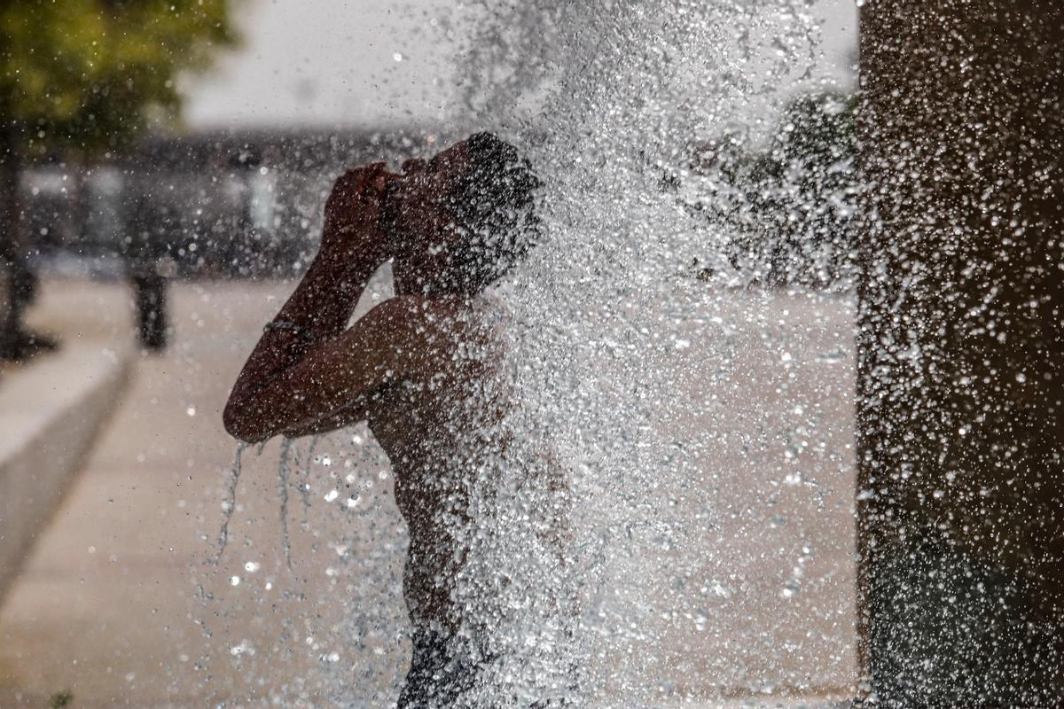 Un joven se refresca en una fuente del Vial Norte, en Córdoba.