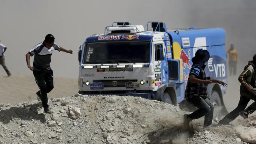 Varios espectadores se alejan a la carrera ante la llegada de un camión Kamaz