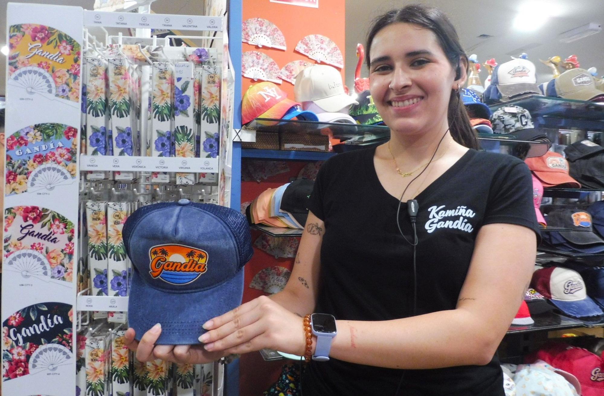 Una dependienta muestra "souvenirs" en una tienda de la playa de Gandia.