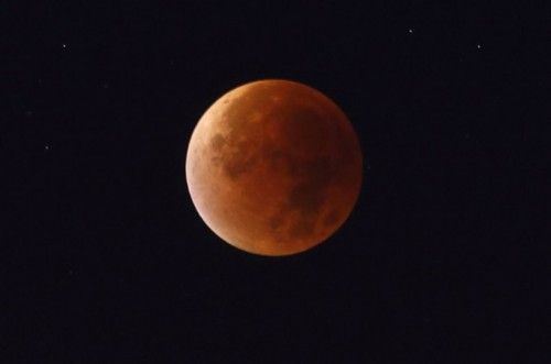 The moon, appearing in a dim red colour, is covered by the Earth's shadow during a total lunar eclipse in Warsaw