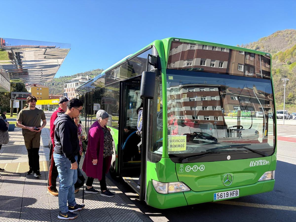 Viajeros subiendo a un autobús de servicios mínimos en Pola de Laviana durante la huelga indefinida de conductores