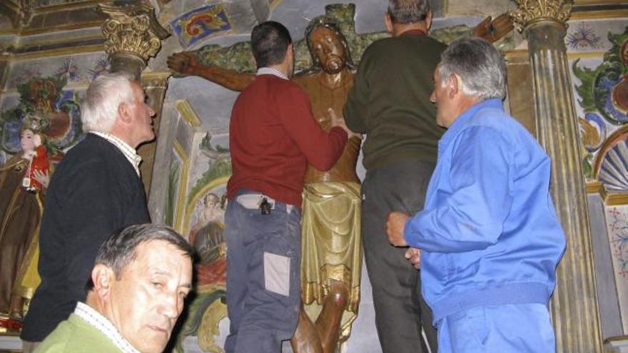 Varios vecinos preparan la imagen del Bendito Cristo de la Vera Cruz que desfila las noches del Jueves y Viernes Santo.