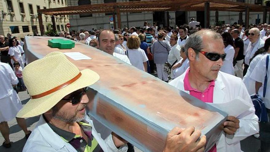 Dos participantes en la protesta de ayer pasean un ataúd simbolizando la muerte de las farmacias.