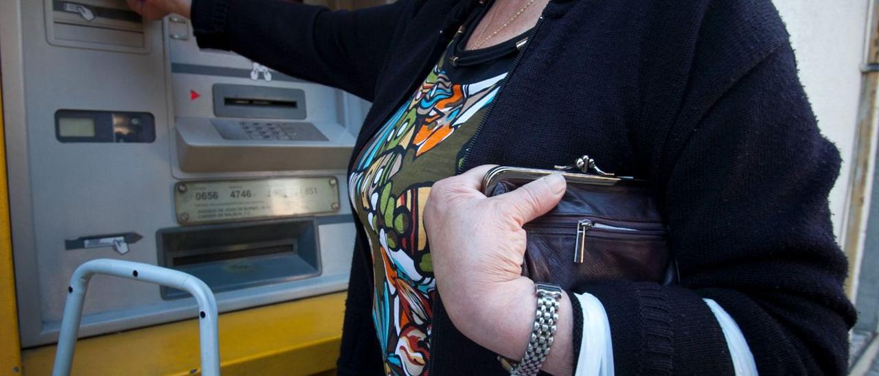 Una mujer saca dinero de un cajero.