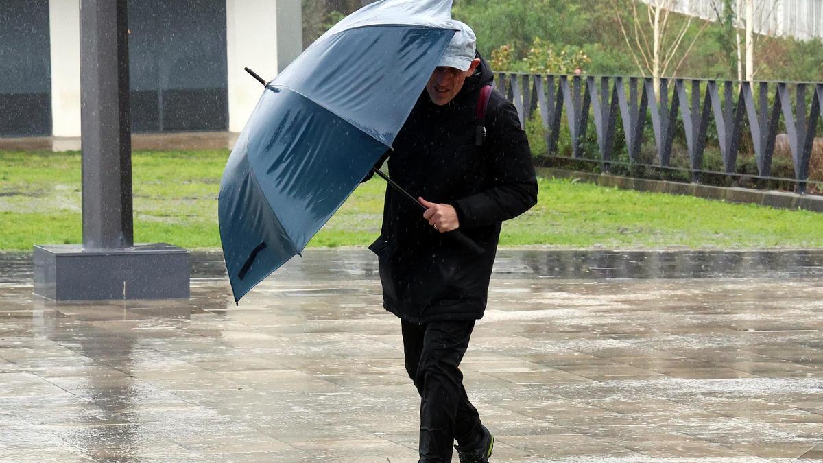 Una persona aguanta su paraguas bajo el viento y la lluvia en Vigo durante este domingo.
