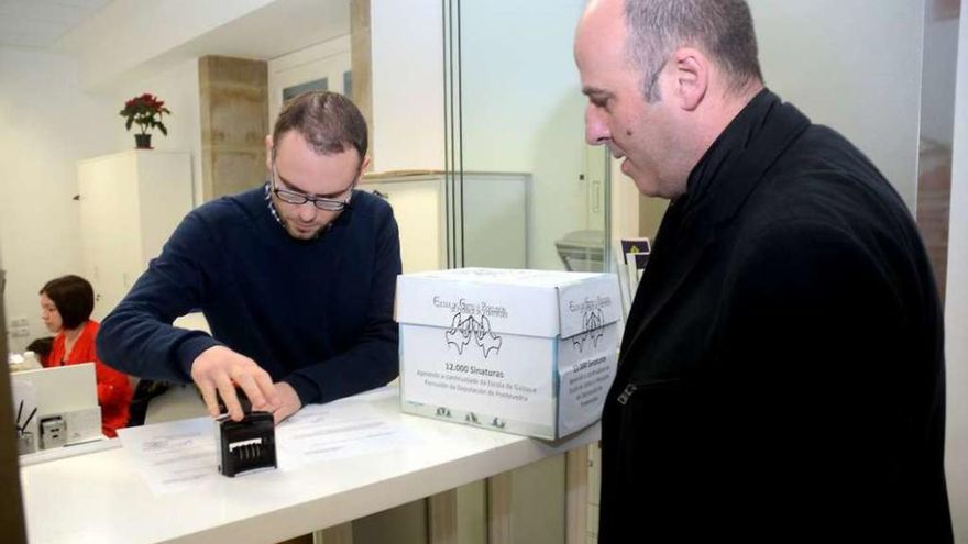 Un funcionario sella el justificante de entrega de las 12.000 firmas ante Hipólito Cabezas. // Rafa Vázquez